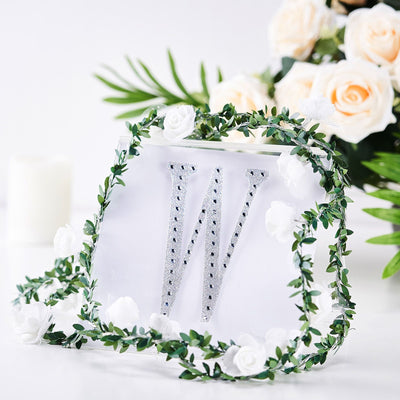 Decorative letter "W" adorned with flowers and greenery.