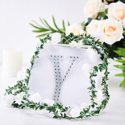 Decorative letter "Y" with rhinestones surrounded by floral greenery.