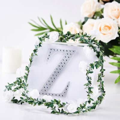 Decorative letter "Z" with rhinestones surrounded by floral accents and greenery.
