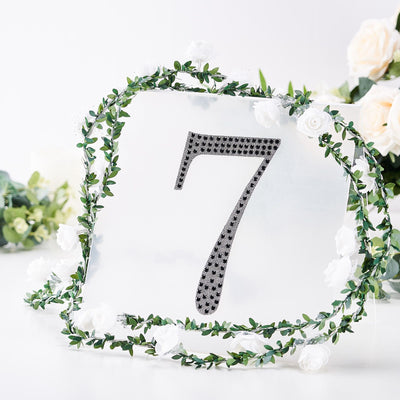 Acrylic table number 7 surrounded by greenery and white flowers.