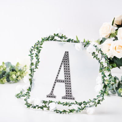 Decorative letter "A" surrounded by greenery and white roses
