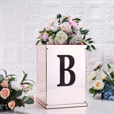 Elegant floral arrangement in a decorative box with letter "B" on a textured background.