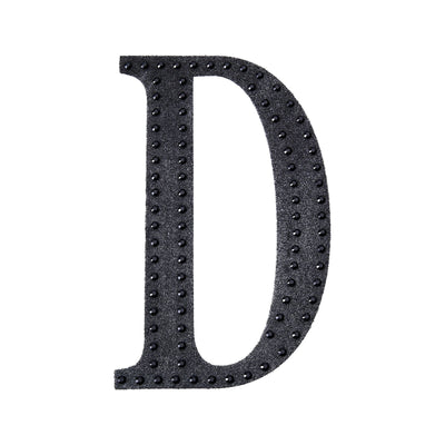 Black decorative letter "D" with studded design on a white background.