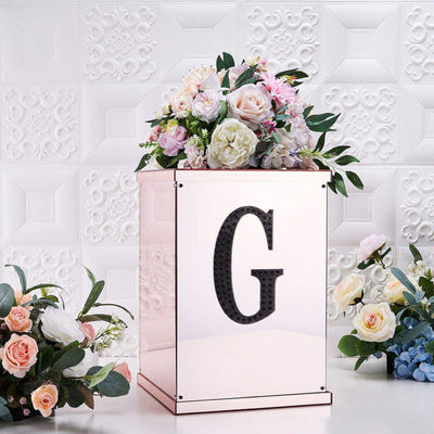 Elegant floral arrangement on a mirrored box with a black "G" accent.