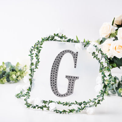 Decorative letter 'G' surrounded by floral accents on a white background