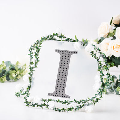 Decorative letter "I" surrounded by floral accents on a white background.