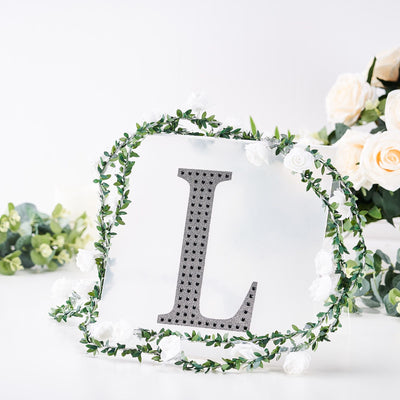 Decorative letter "L" with floral accents on a white background.