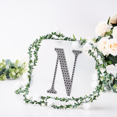 Decorative letter "N" adorned with flowers and greenery on a white background.