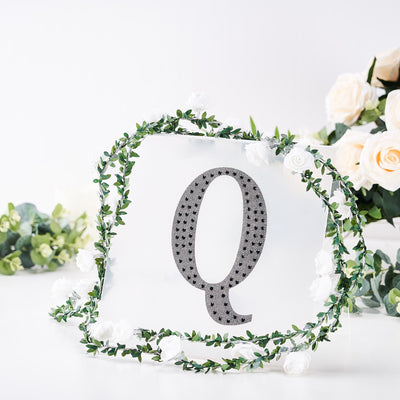 Decorative letter "Q" with floral wreath backdrop