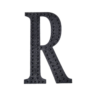 Black decorative letter "R" with studded design on a plain background