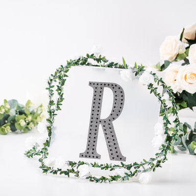 Decorative letter "R" with floral accents on a white background