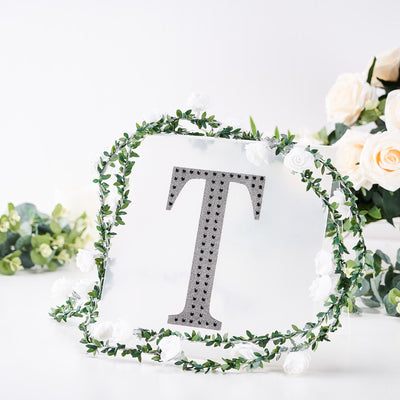 Decorative letter T with floral wreath on a white background