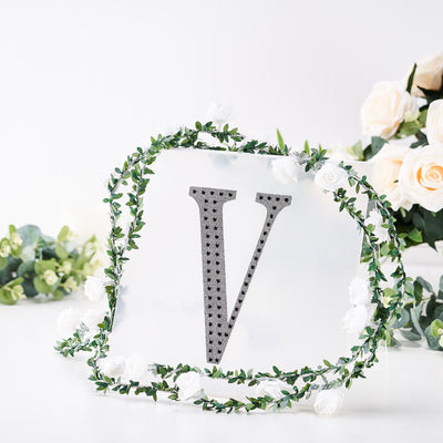 Decorative letter "V" surrounded by floral accents on a clear backdrop.