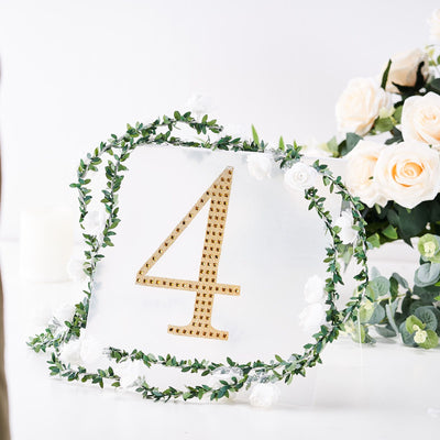 Gold rhinestone table number 4 surrounded by floral decor on a clear acrylic base.