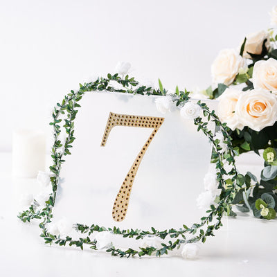 Elegant table number 7 with gold studs and floral greenery decoration.