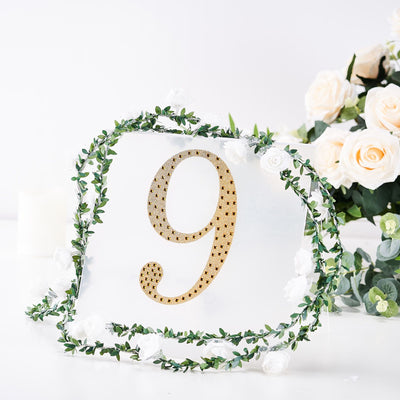 Gold number 9 table sign surrounded by greenery and white flowers