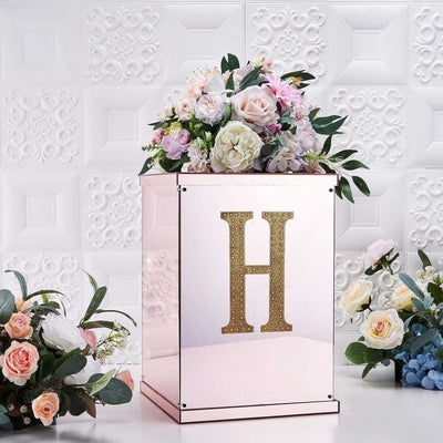 Elegant floral arrangement in a mirrored box with a gold letter "H".