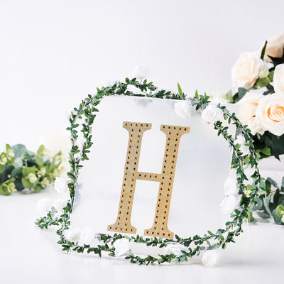 Gold letter H surrounded by floral wreath on a clear background.
