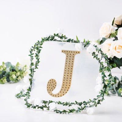 Decorative gold letter "J" surrounded by floral arrangement
