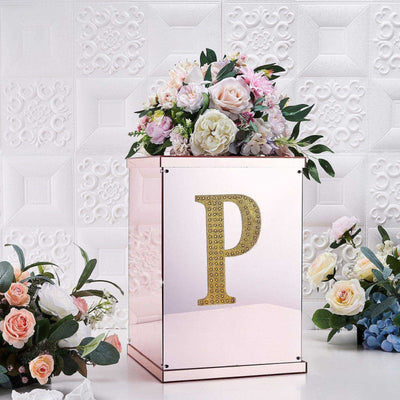 Decorative floral arrangement in a mirrored box with a golden letter "P".