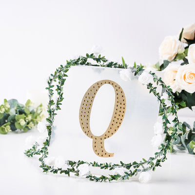 Decorative letter "Q" surrounded by flowers and greenery.
