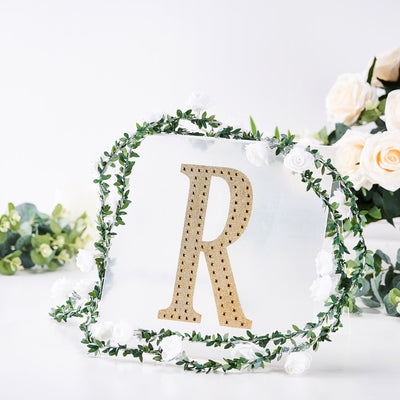 Decorative letter "R" with floral accents on a clear background.