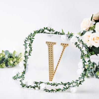 Gold letter "V" decor with floral accents on a clear background
