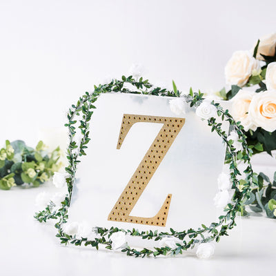 Gold letter "Z" decor with floral garland on a white backdrop.