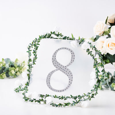 Decorative table number 8 adorned with rhinestones and floral greenery