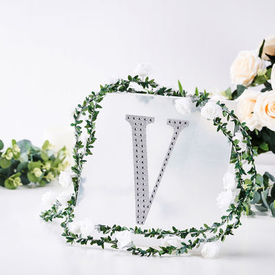 Decorative letter "V" adorned with floral accents on a clear backdrop.