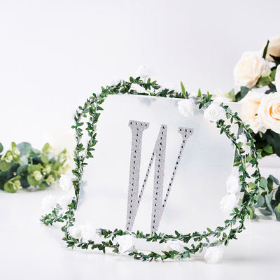 Decorative letter "W" with floral accents on a clear backdrop.