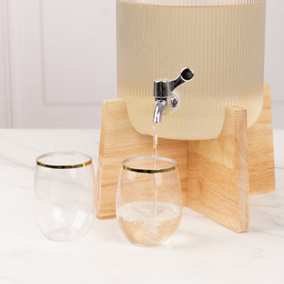 Drink dispenser with clear glasses on a marble surface.