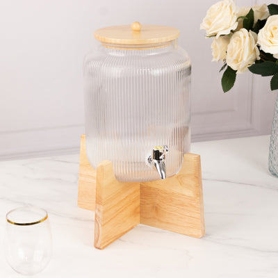 Glass beverage dispenser with wooden lid and stand, featuring a spigot.