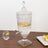 Vintage glass beverage dispenser with ornate design and lemon slices.