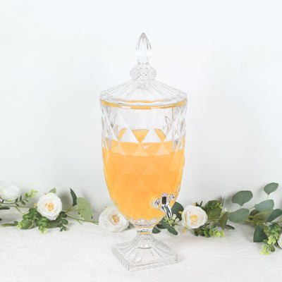 Crystal beverage dispenser filled with orange drink on a plain background.