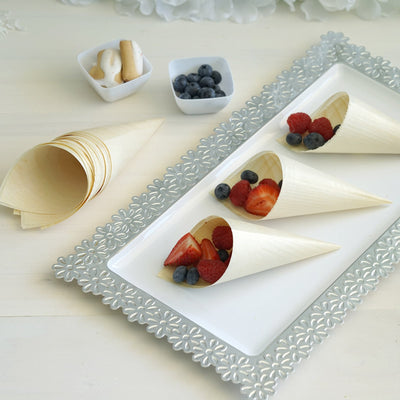 Wooden dessert cones filled with fresh berries on a decorative platter.