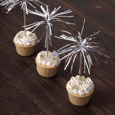 Decorative cupcakes with silver fringe toppers on a wooden surface.