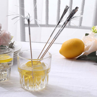 Cocktail glasses with decorative stirrers and lemon slices on a table.