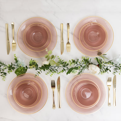 Elegant pink and gold dinner plates arranged with cutlery and greenery.