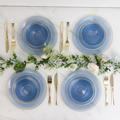 Elegant blue dinner plates with gold trim, arranged with cutlery and greenery.