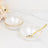 Elegant white bowls with gold rim and a gold spoon on marble background.