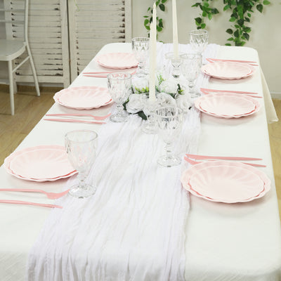 Elegant pink plates and glassware set on a white table for a stylish dining setup.