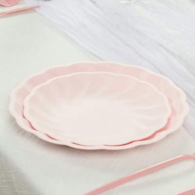 Pink scalloped plates stacked on a textured tablecloth.
