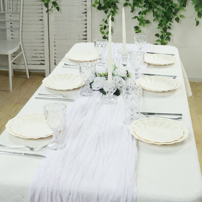Elegant dining table set with white plates, glassware, and candles.