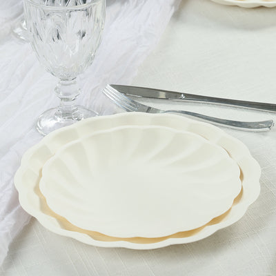 Elegant white scalloped plates stacked on a table setting.