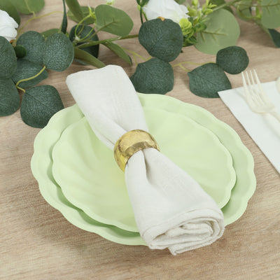 Green scalloped plates with a napkin and holder on a rustic wooden table.