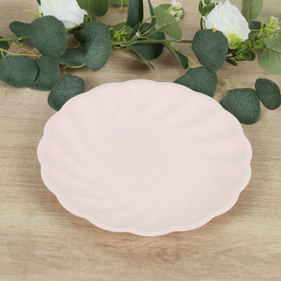 Pink scalloped plate on a wooden surface with greenery.
