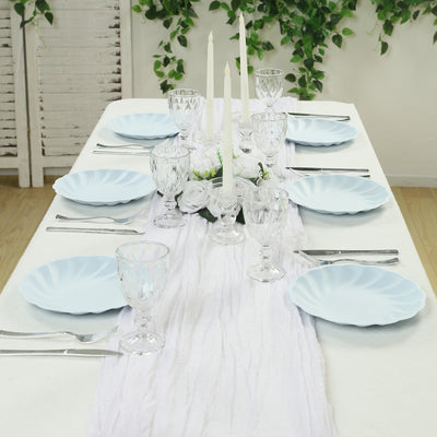 Elegant blue plates and crystal glassware set on a dining table adorned with candles and flowers.