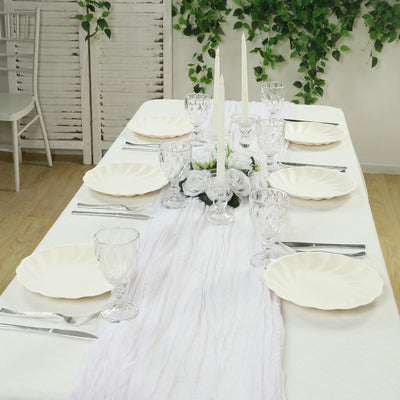 Elegant dining table set with white plates, candles, and floral centerpiece.