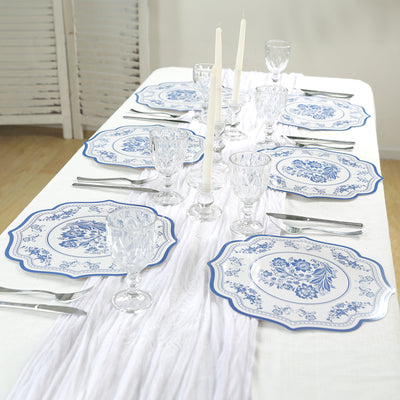 Elegant blue and white dining set with plates, glasses, and candles on a table.